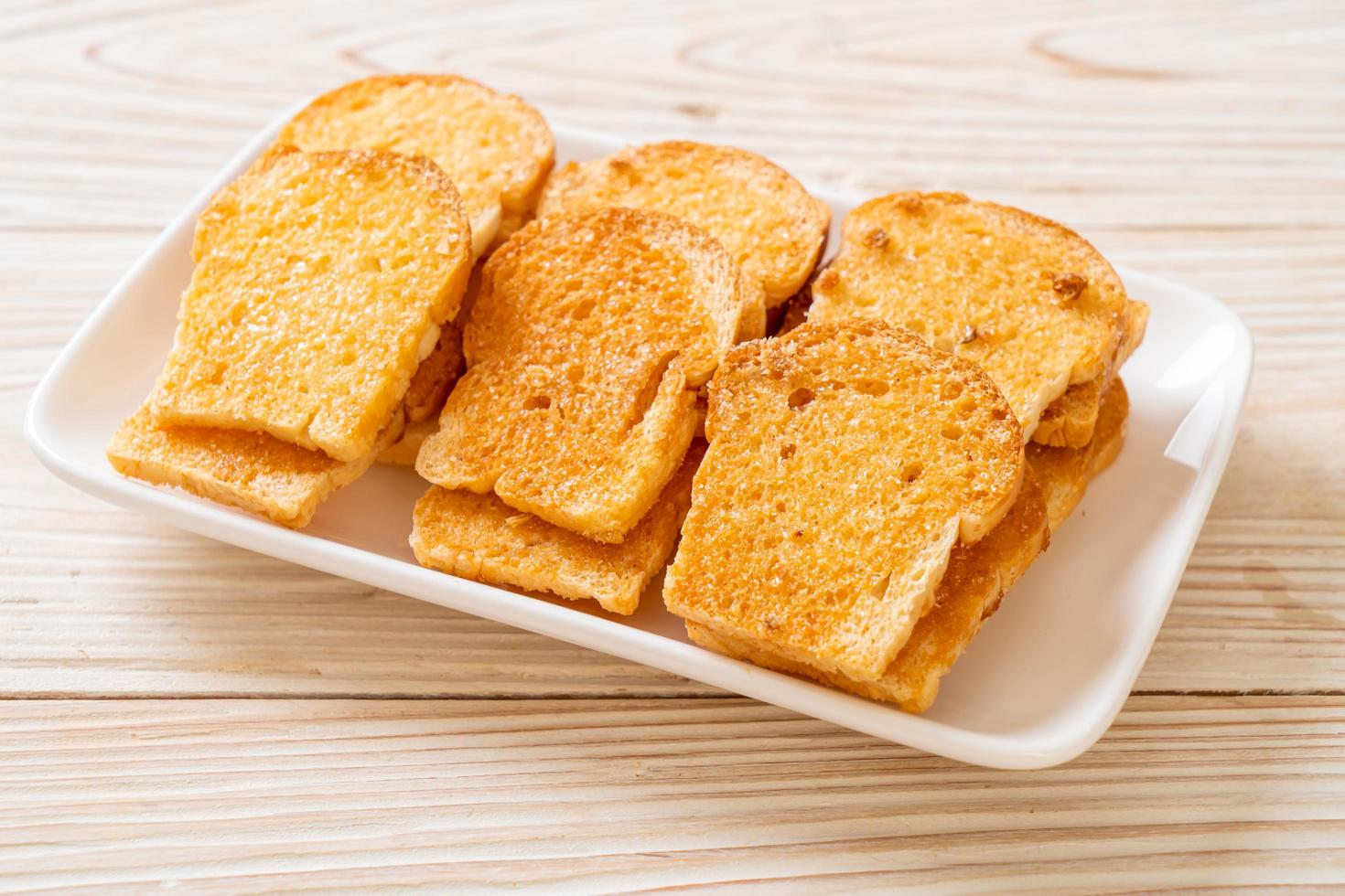 Baked crispy bread with butter and sugar on plate photo