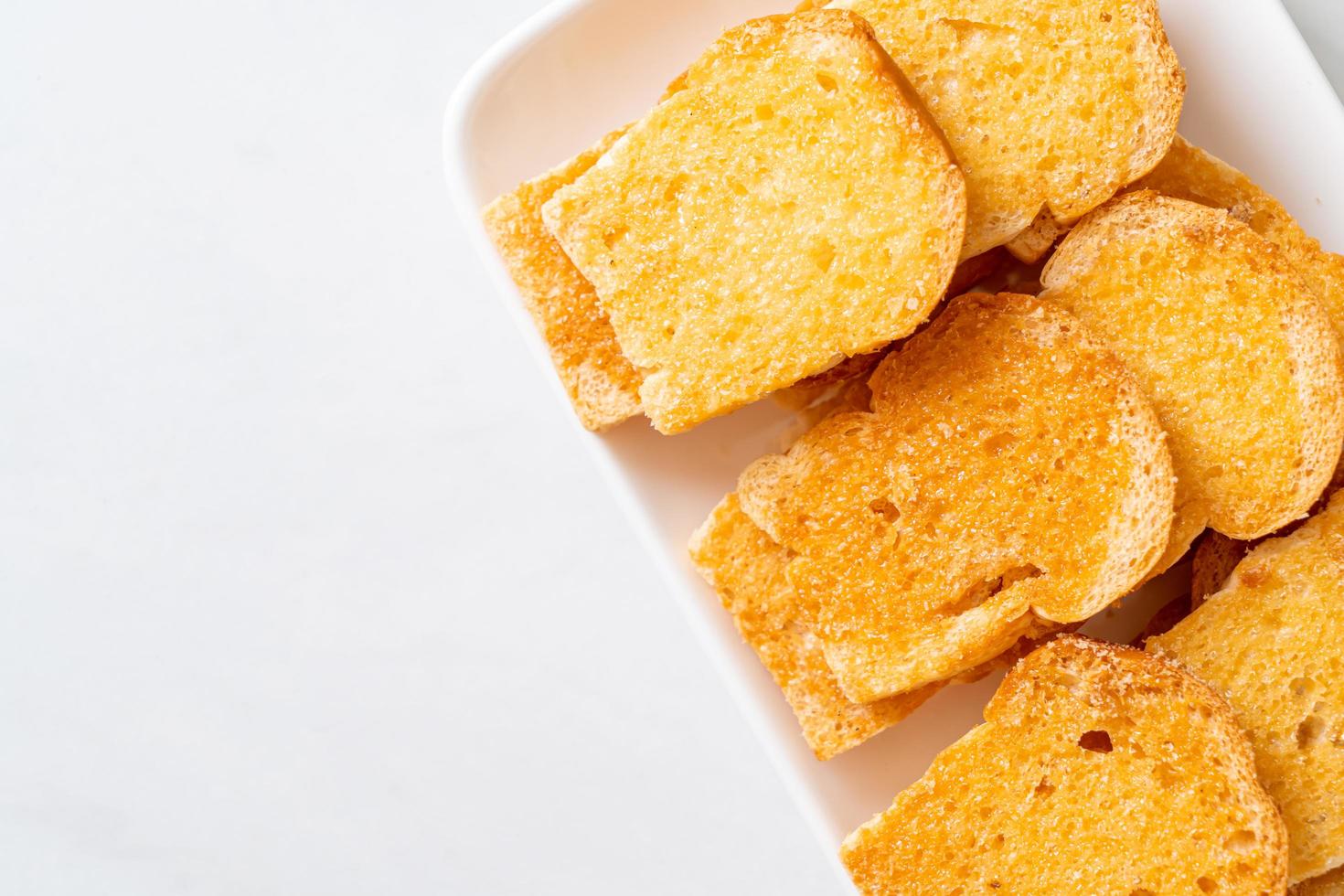 Baked crispy bread with butter and sugar on plate photo