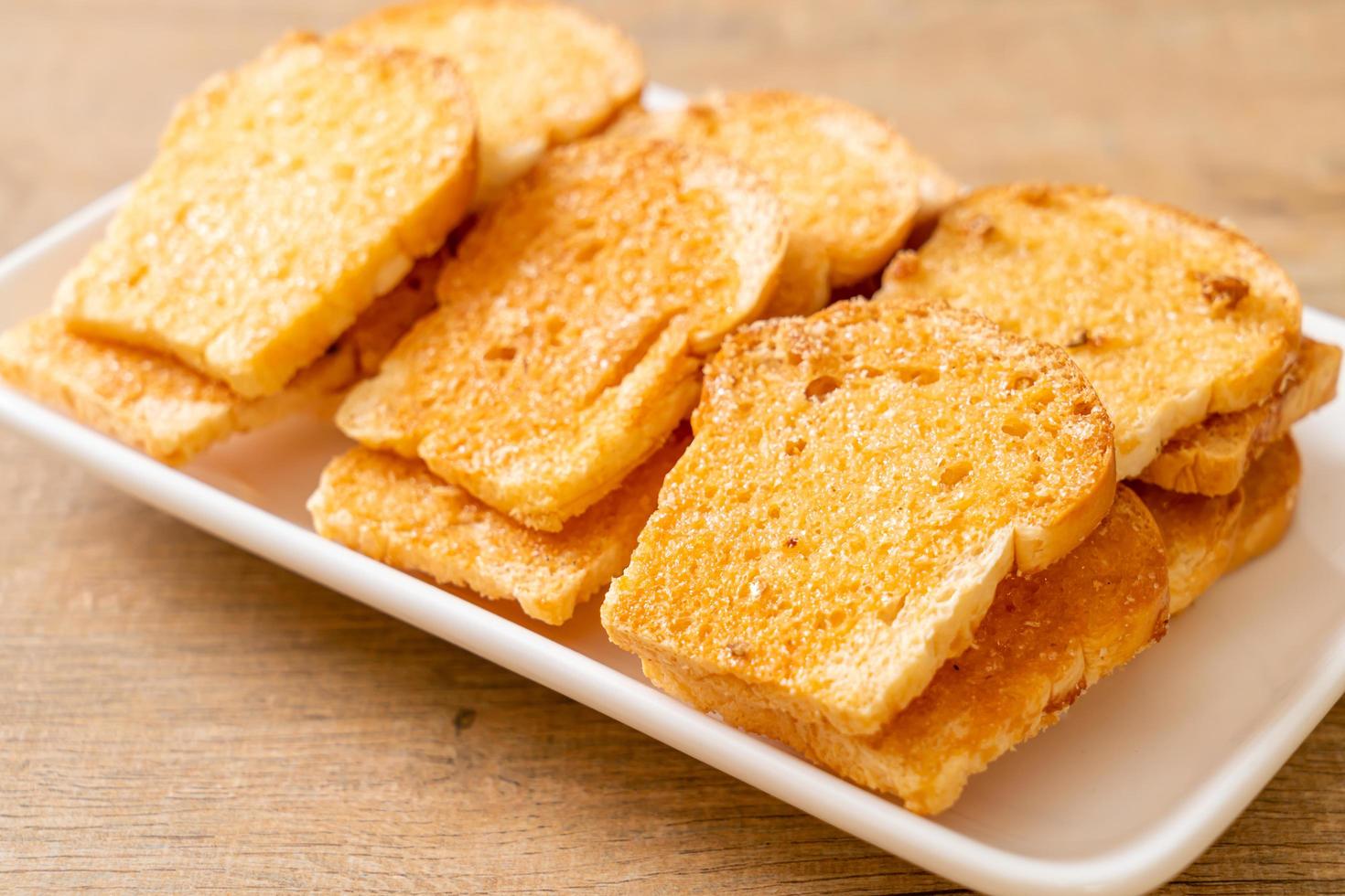 Baked crispy bread with butter and sugar on plate photo