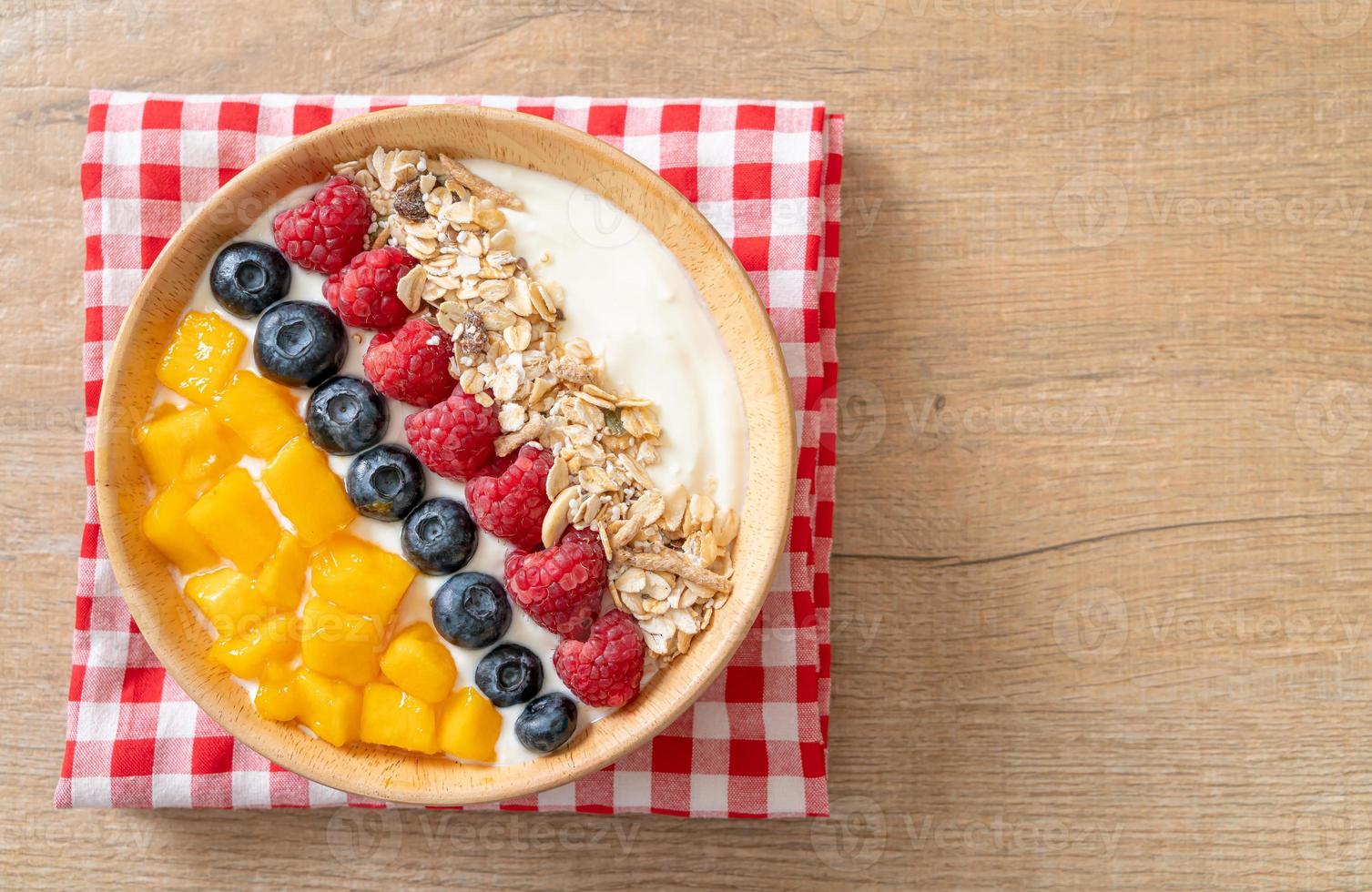 Homemade yogurt bowl with raspberry, blueberry, mango, and granola - healthy food style photo