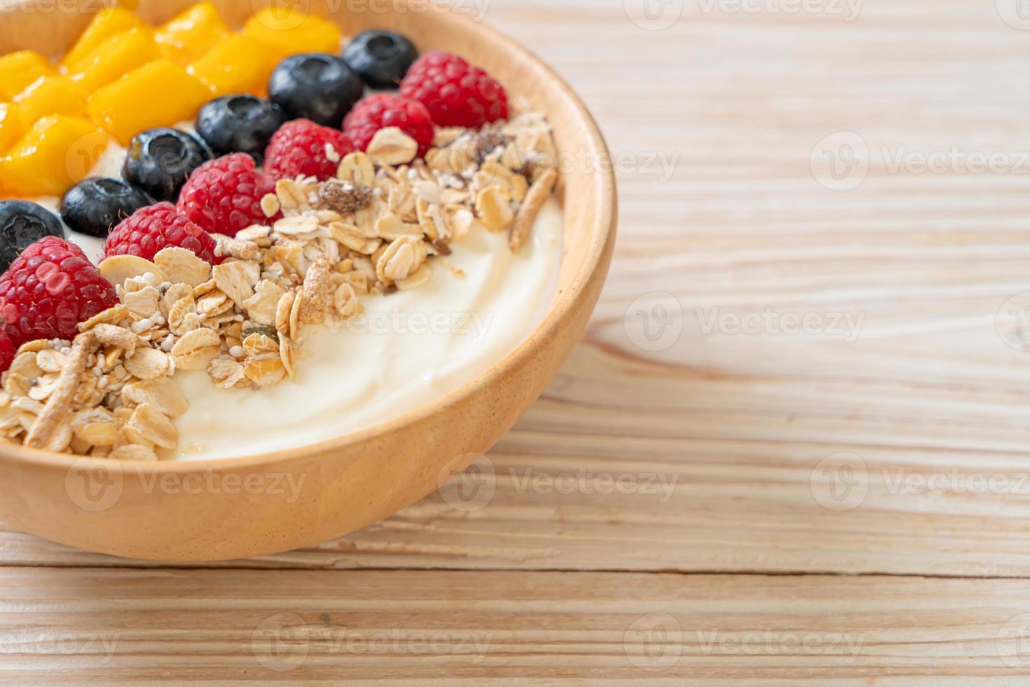 Homemade yogurt bowl with raspberry, blueberry, mango, and granola - healthy food style photo