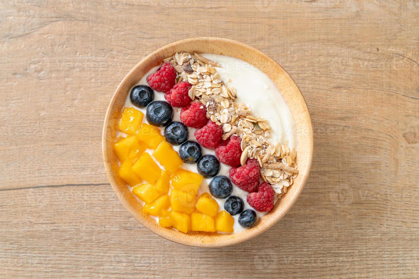 Homemade yogurt bowl with raspberry, blueberry, mango, and granola - healthy food style photo