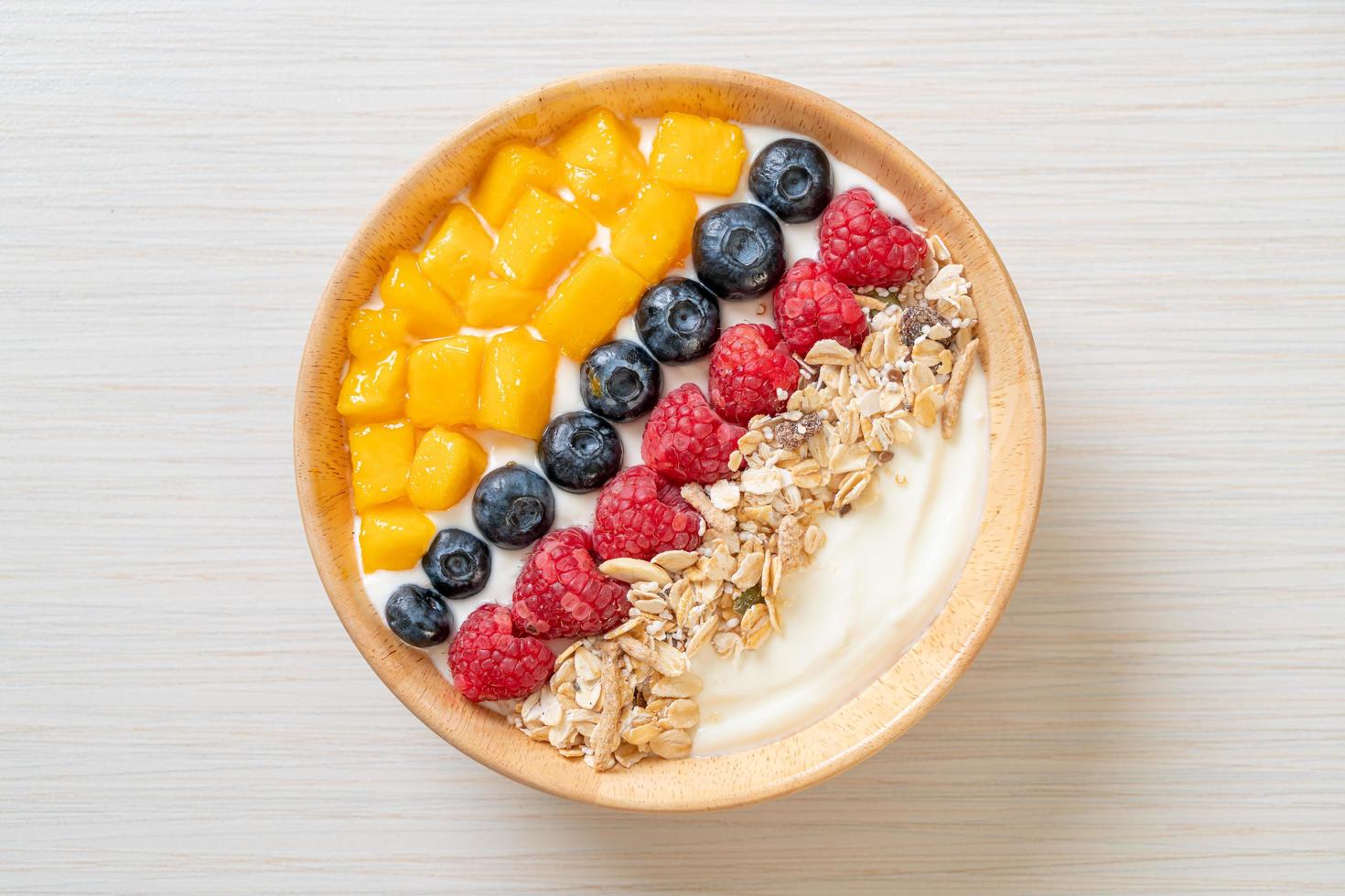 Homemade yogurt bowl with raspberry, blueberry, mango, and granola - healthy food style photo