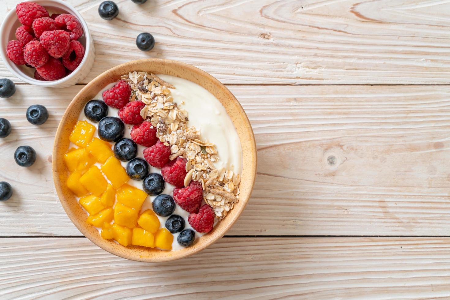 Homemade yogurt bowl with raspberry, blueberry, mango, and granola - healthy food style photo