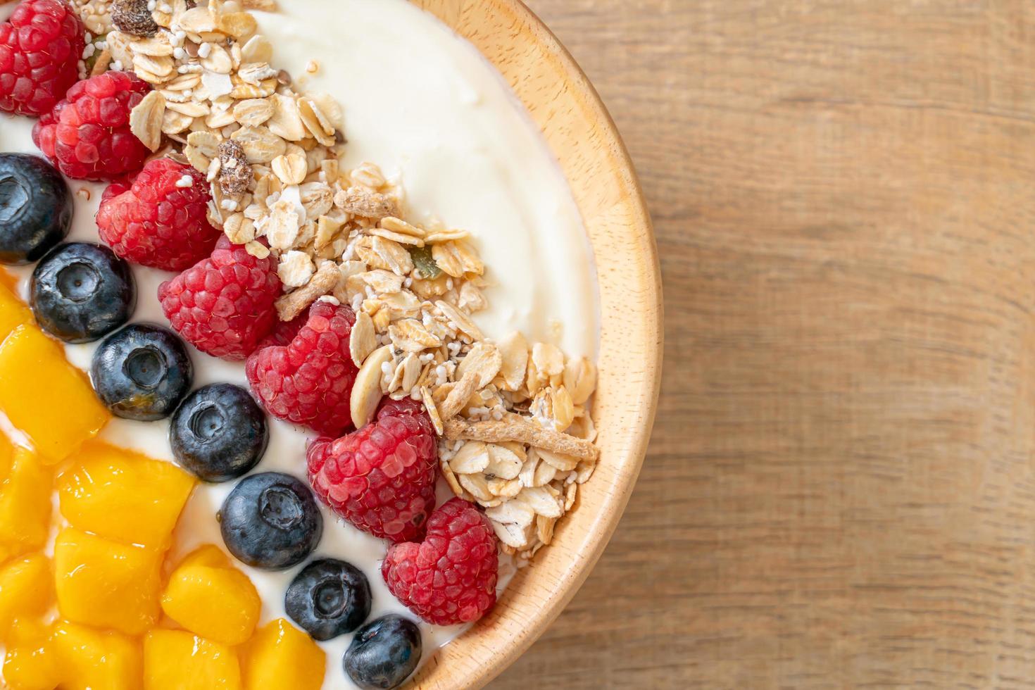 Homemade yogurt bowl with raspberry, blueberry, mango, and granola - healthy food style photo