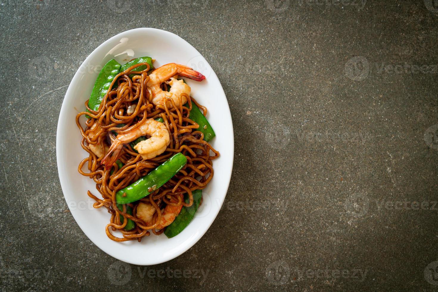 fideos yakisoba salteados con guisantes y camarones - estilo de comida asiática foto