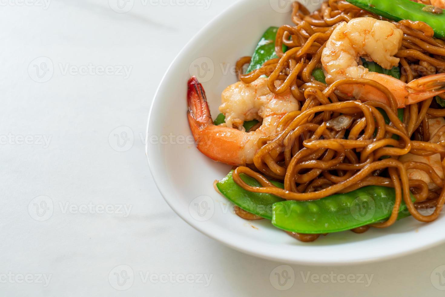 fideos yakisoba salteados con guisantes y camarones - estilo de comida asiática foto