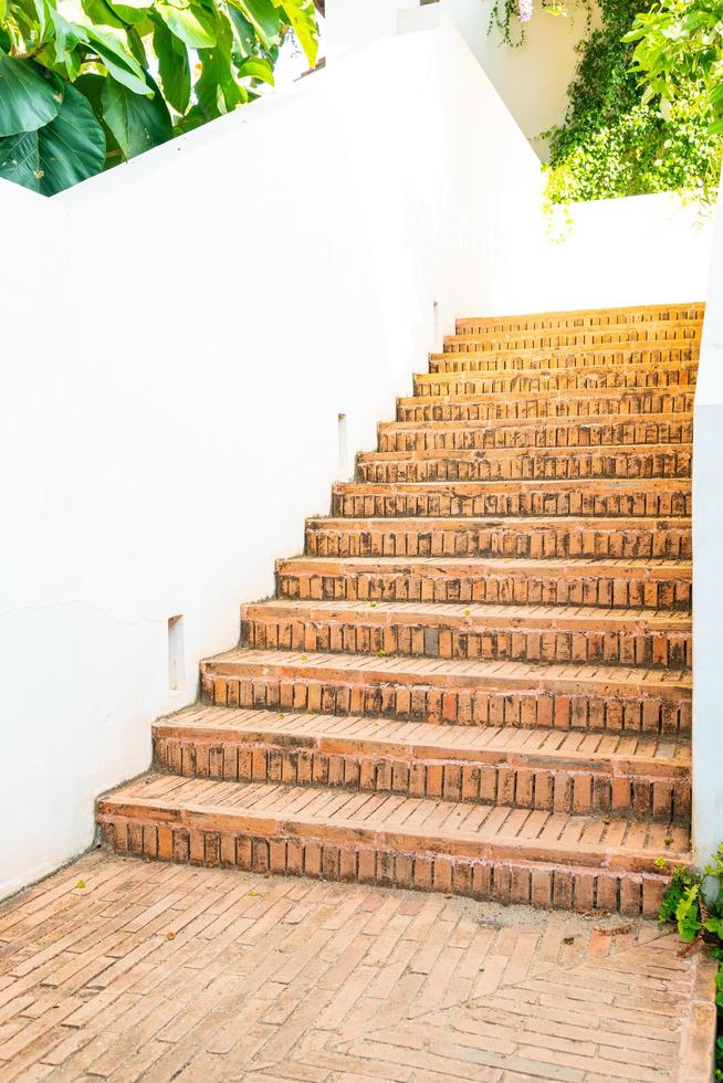 Paso de escalera de ladrillo al aire libre con pared blanca foto