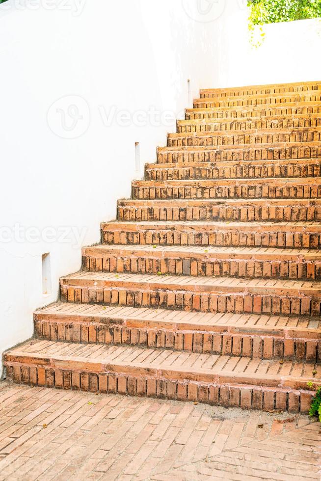 Paso de escalera de ladrillo al aire libre con pared blanca foto