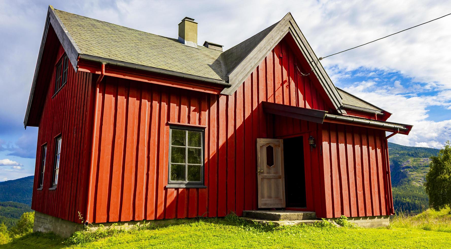 Hermosa cabaña de madera roja en la colina en la naturaleza de Noruega. foto