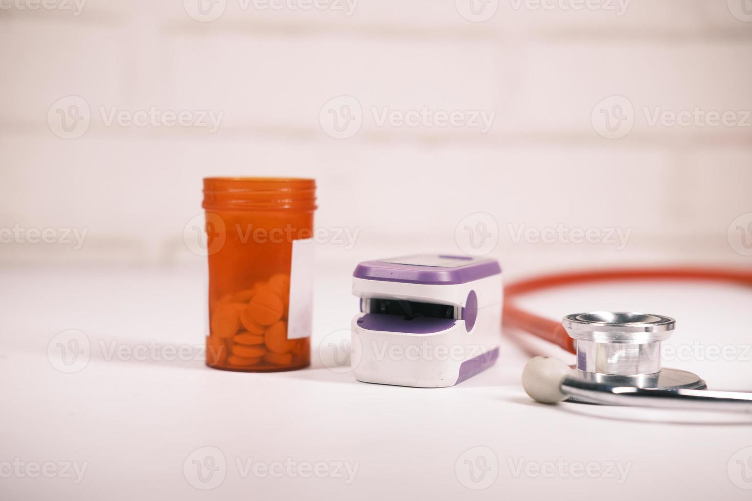 Pill container, stethoscope, and pulse oximeter on table photo