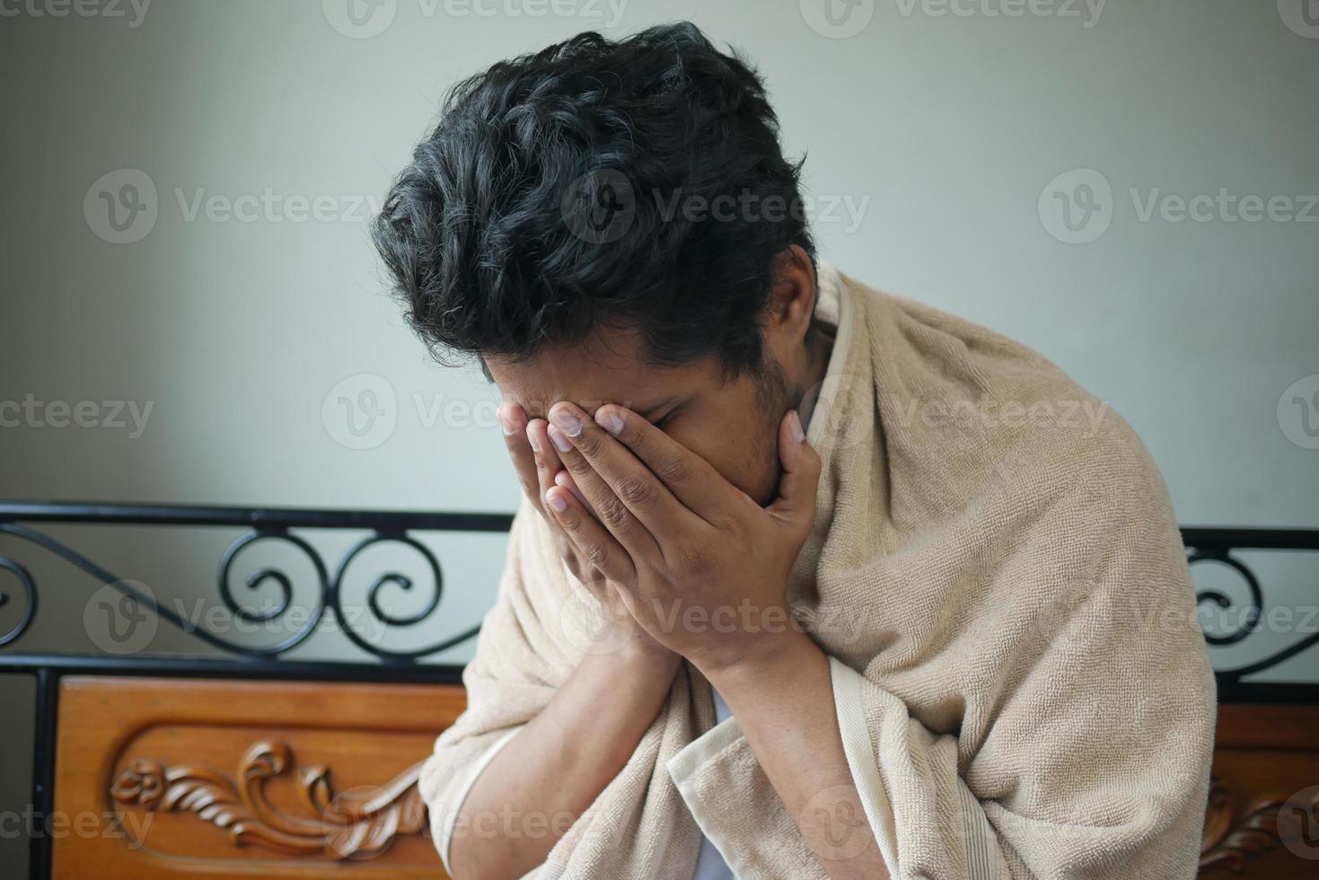 Mature man in blanket coughing while sited on bed photo
