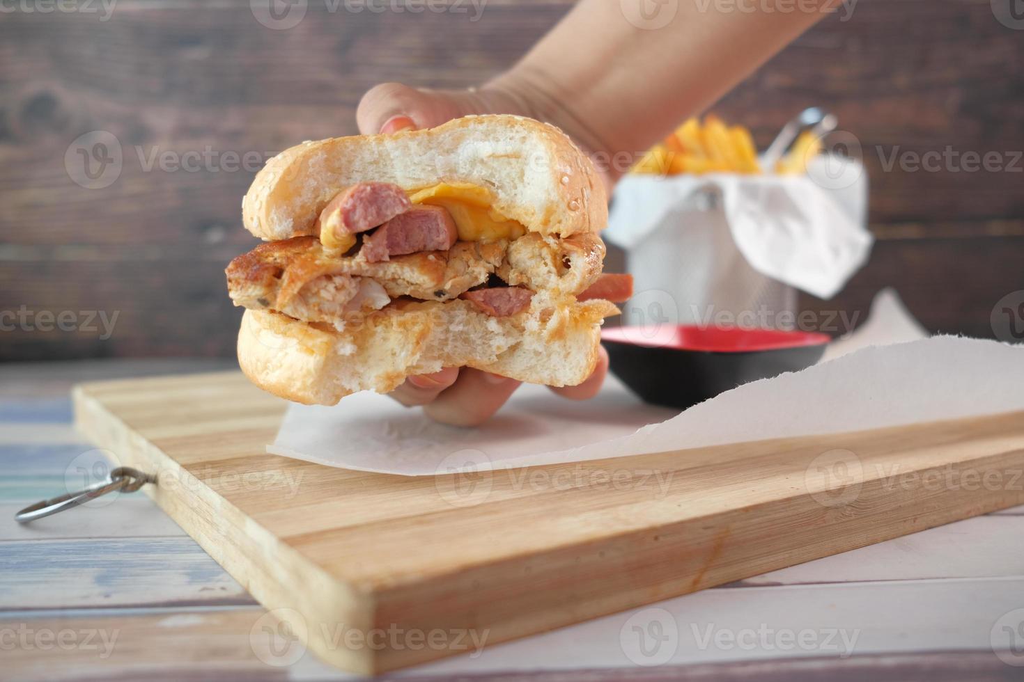 Mano sujetando hamburguesa de ternera en la mesa de cerca foto