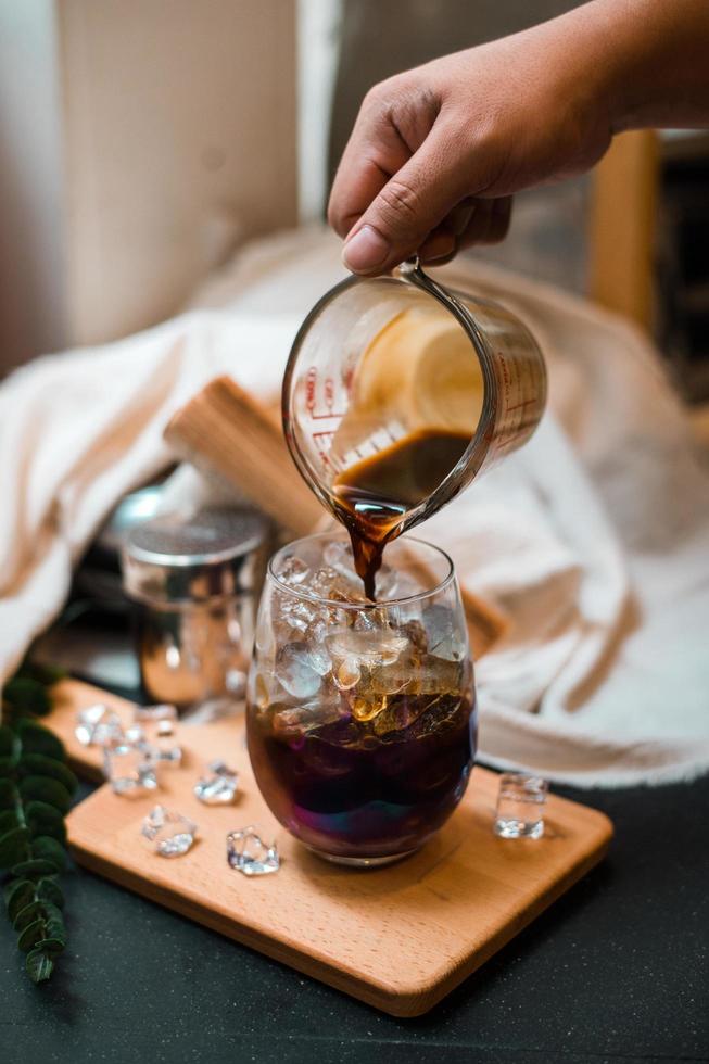 Barista pouring milk into a glass of iced coffee photo