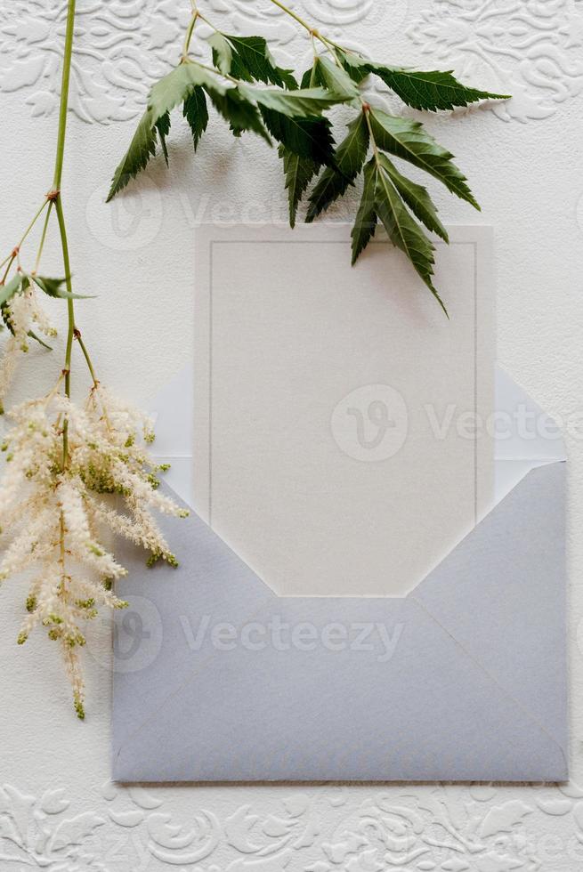 invitación de boda en un sobre gris con ramitas verdes foto