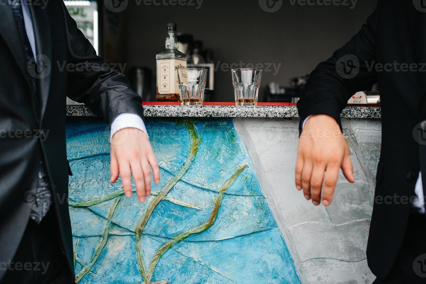 two guys at the bar drink whiskey from crystal glasses photo
