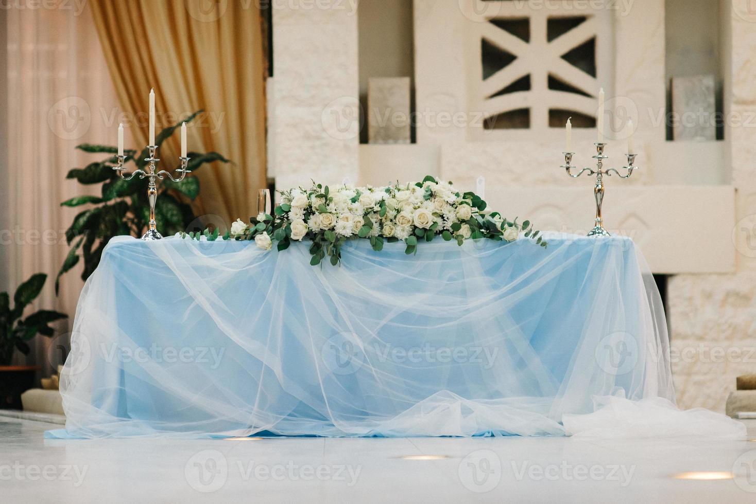 el presidium de los recién casados en el salón de banquetes del restaurante está decorado con velas y plantas verdes foto