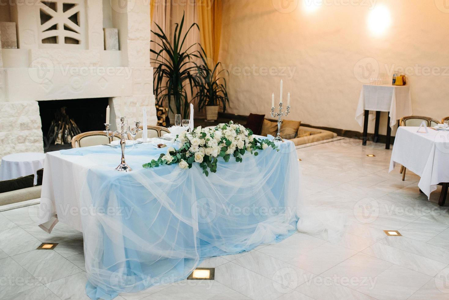 el presidium de los recién casados en el salón de banquetes del restaurante está decorado con velas y plantas verdes foto