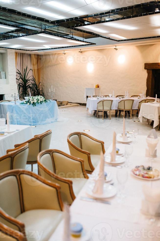 The presidium of the newlyweds in the banquet hall of the restaurant is decorated with candles and green plants photo