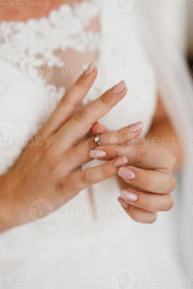 the bride gently touches her dear engagement ring photo