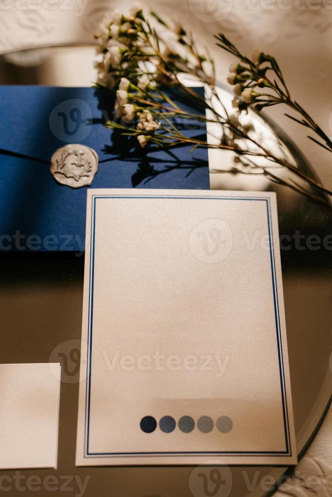 wedding invitation in a gray envelope on a table with green sprigs photo