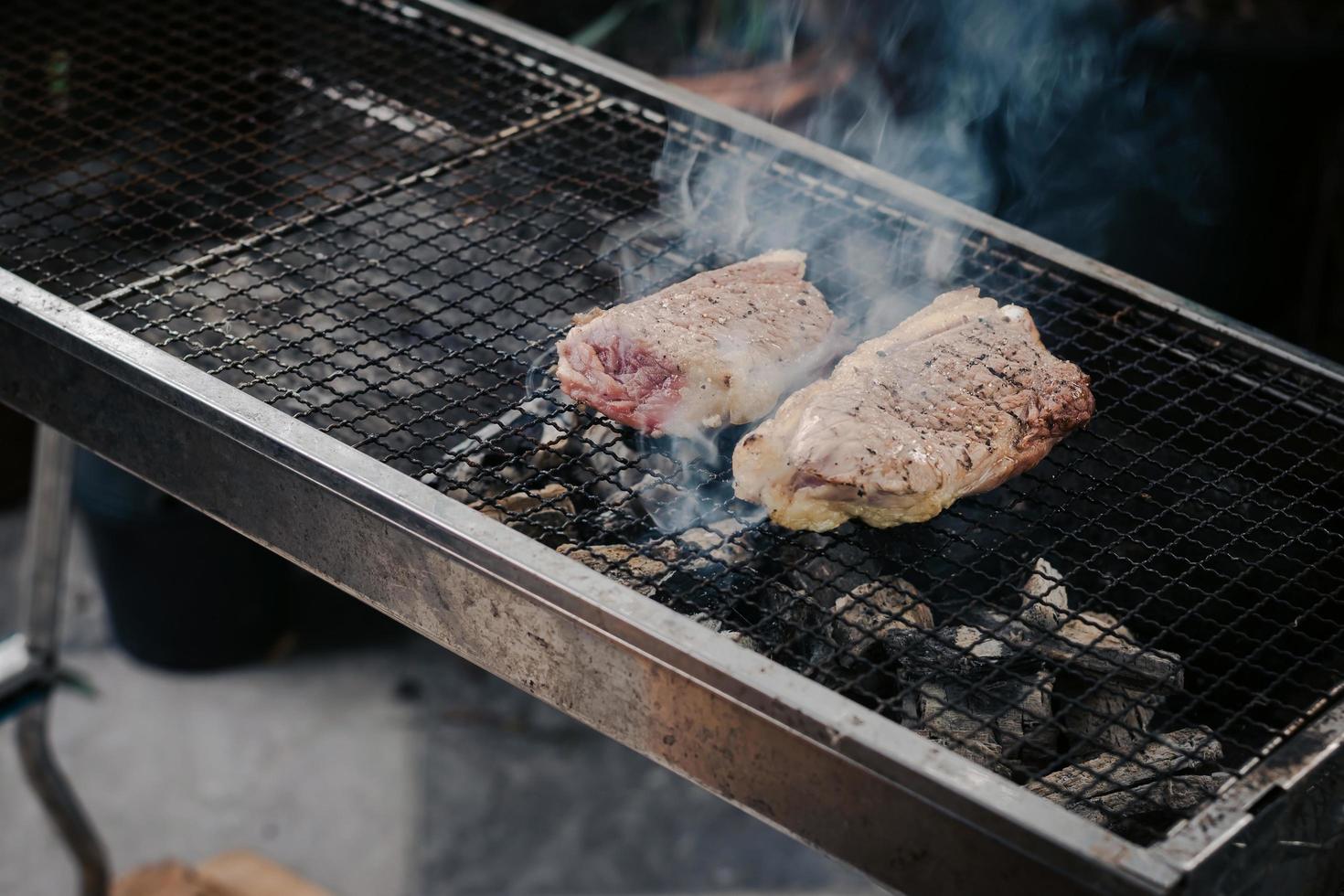Asa la carne en la parrilla de carbón para cocinar bistecs foto