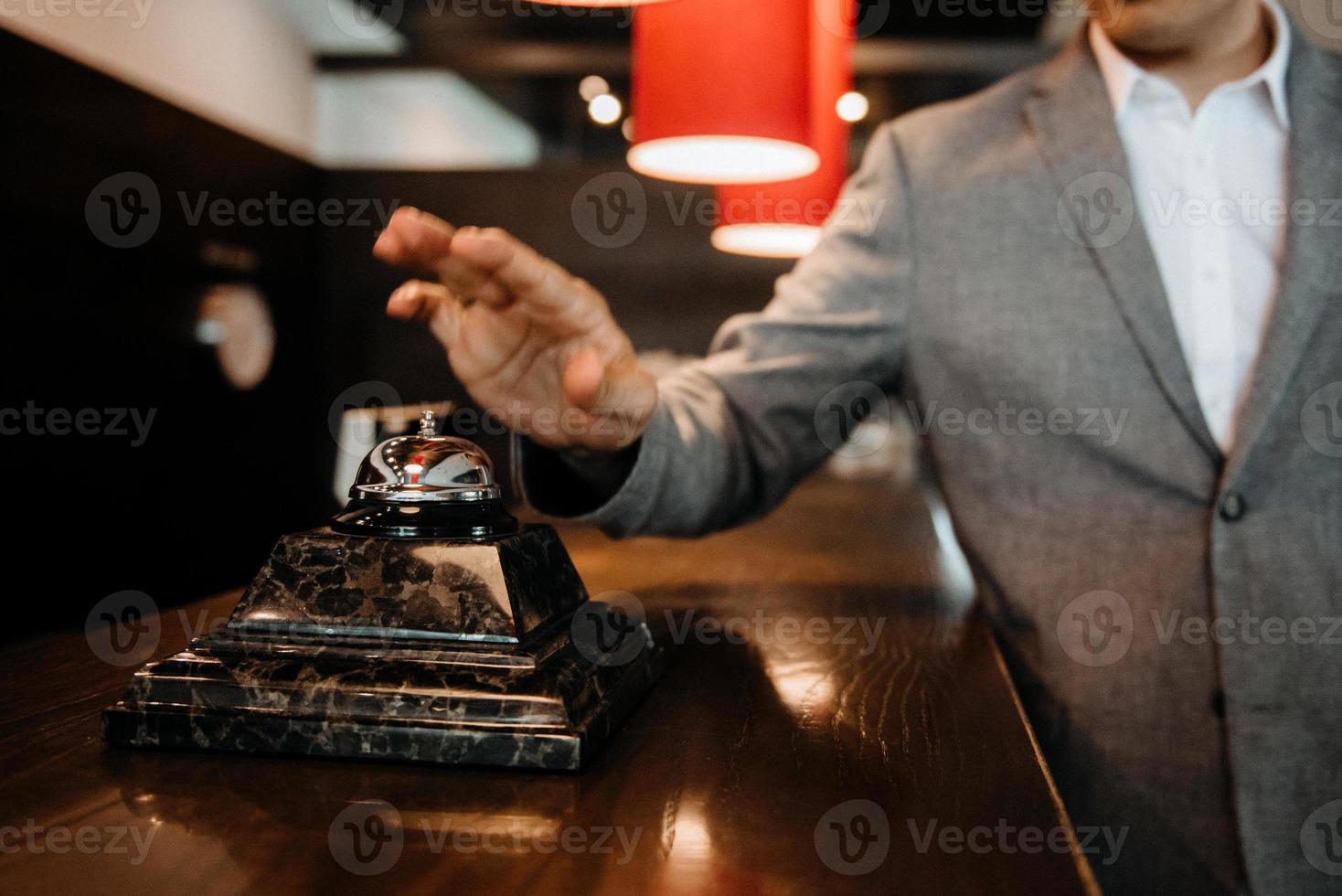 t el chico hace clic en el timbre en la recepción del hotel foto