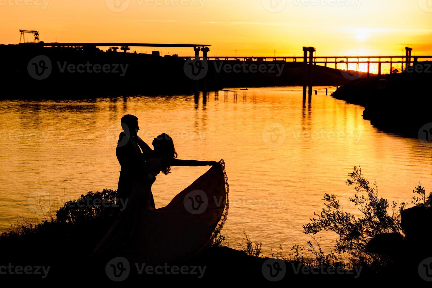 Siluetas de una feliz pareja joven chico y chica sobre un fondo de naranja atardecer en el desierto de arena foto