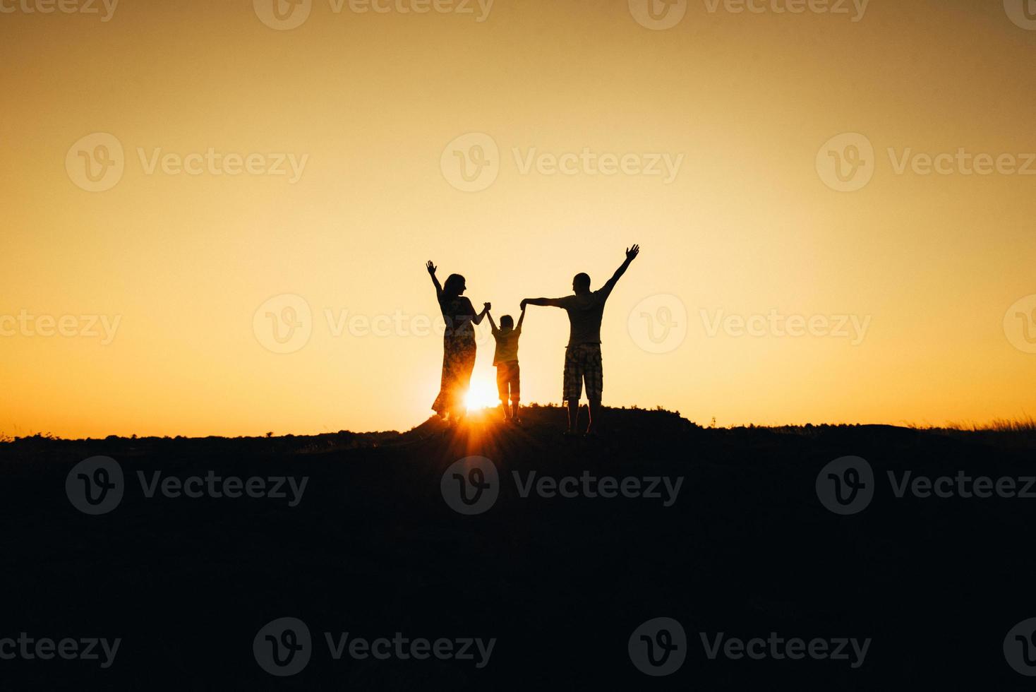 silhouettes of a happy young happy family against an orange sunset photo