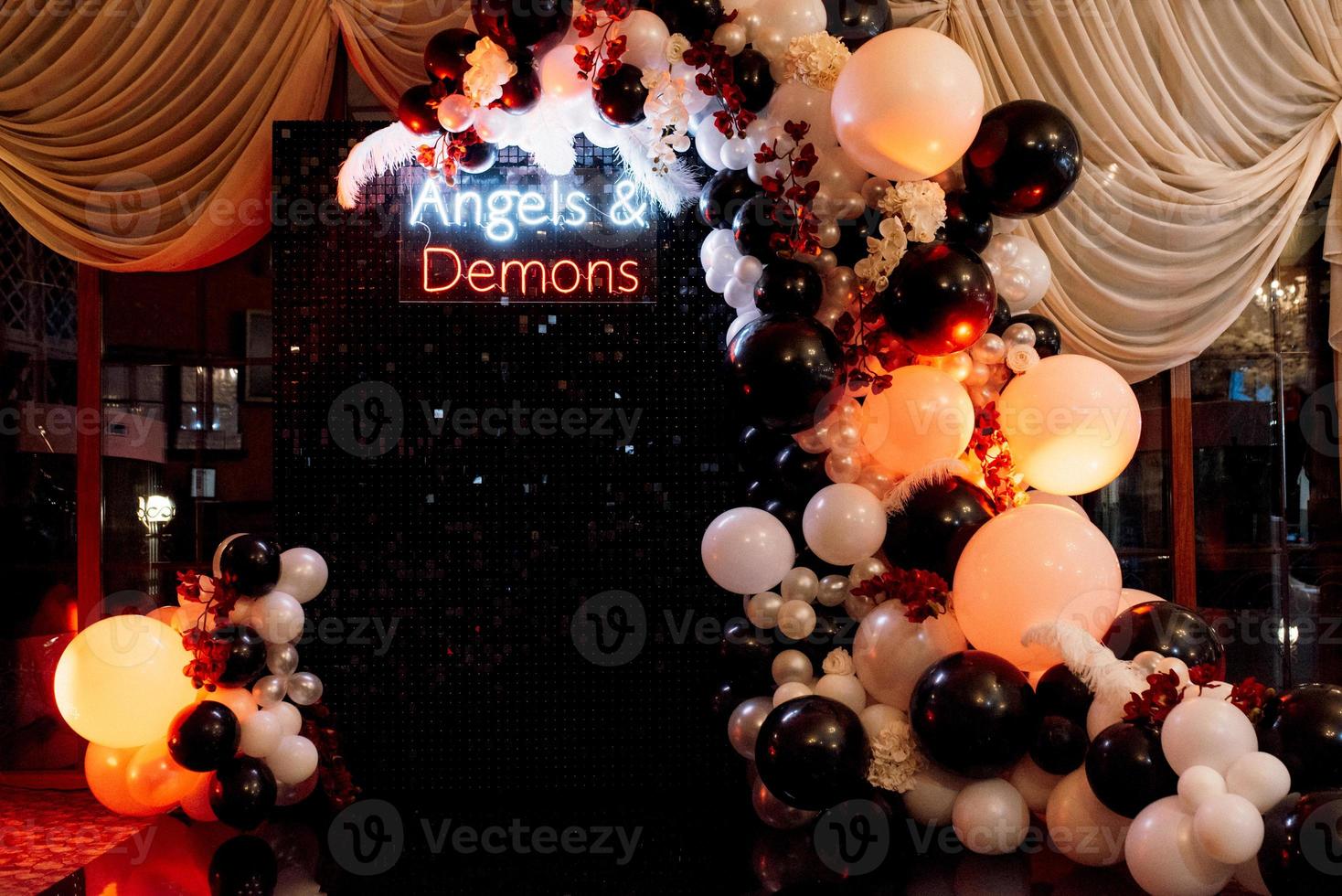 una zona de fotos temática de ángeles y demonios en negro con bolas blancas y negras