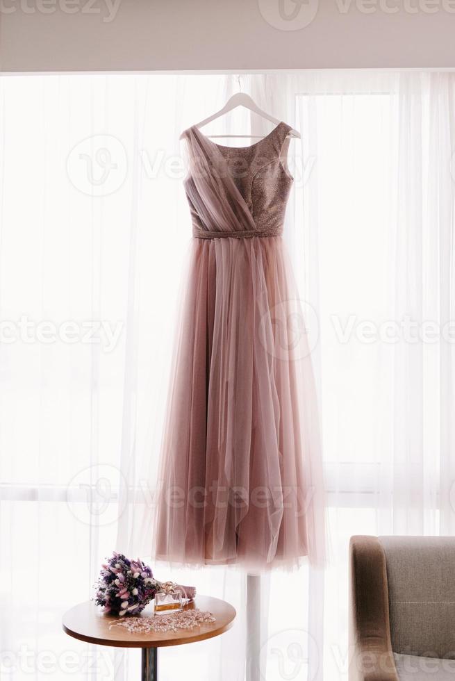 pink wedding dress on the background of the window with the bride's bouquet photo