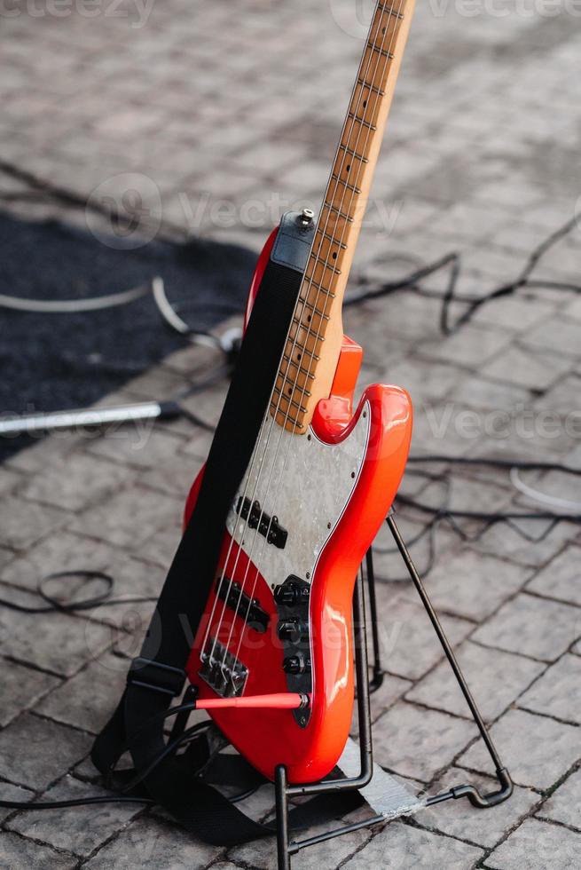 red electric guitar on a stand is on the ground photo