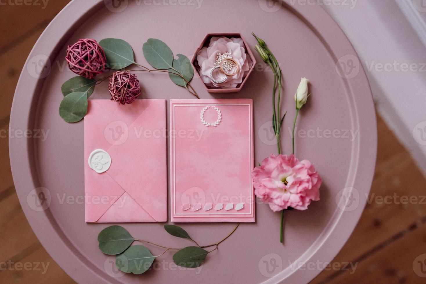 wedding invitation in a gray envelope on a table with green sprigs photo