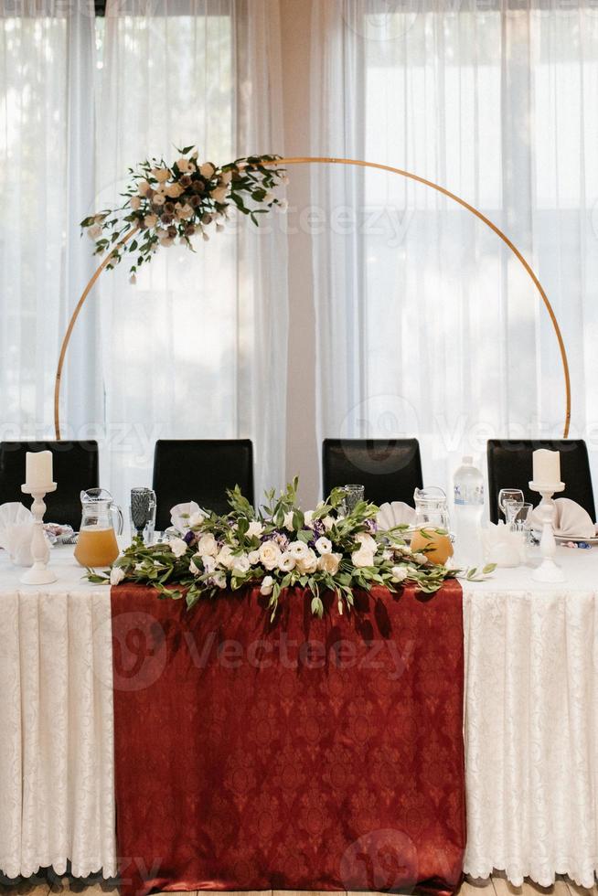 The presidium of the newlyweds in the banquet hall of the restaurant is decorated with candles and green plants photo