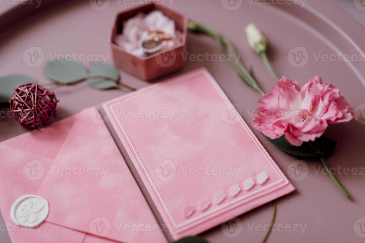 wedding invitation in a gray envelope on a table with green sprigs photo