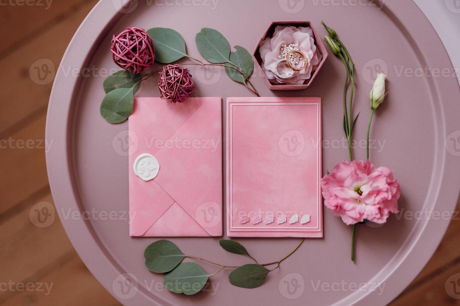 wedding invitation in a gray envelope on a table with green sprigs photo