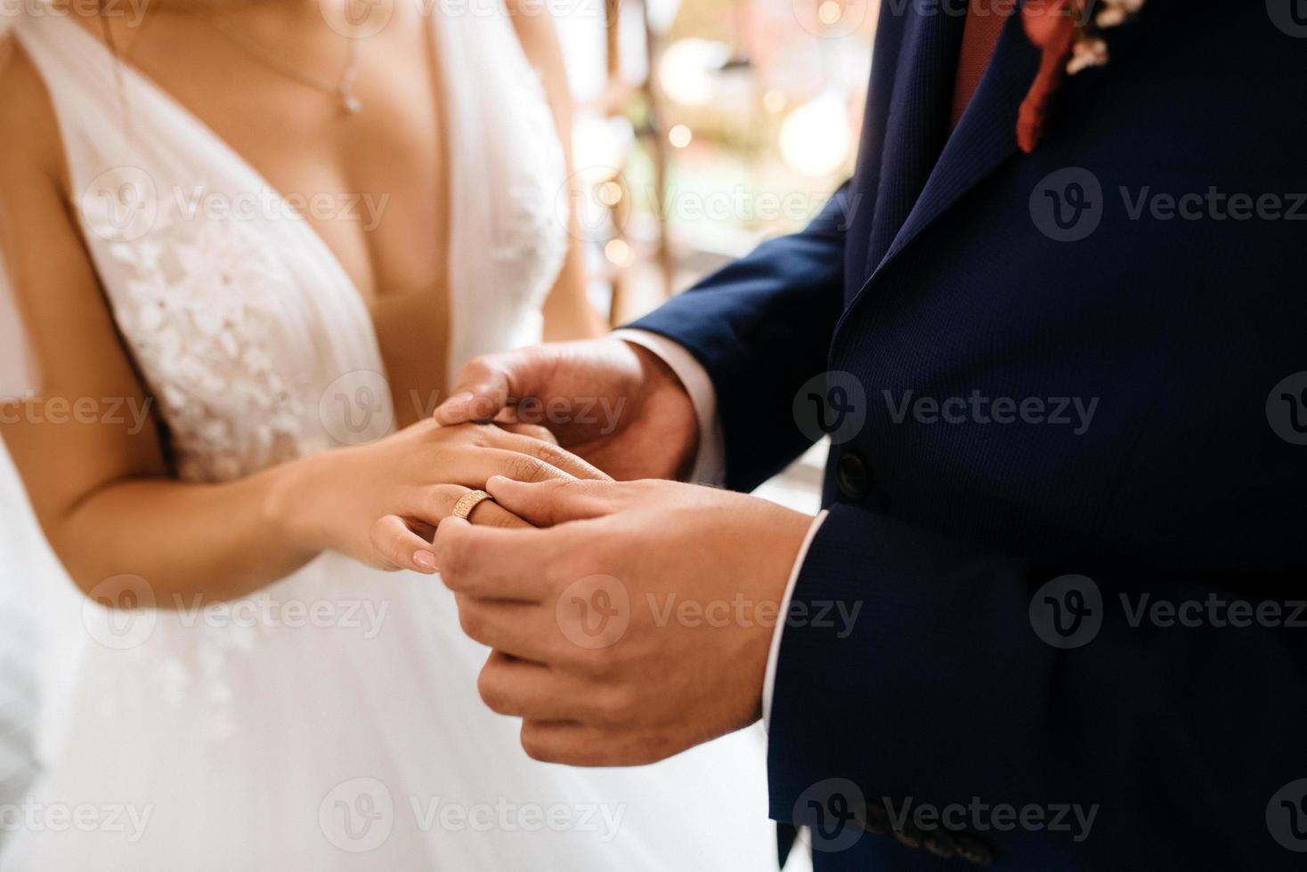 groom puts bride on wedding ring photo
