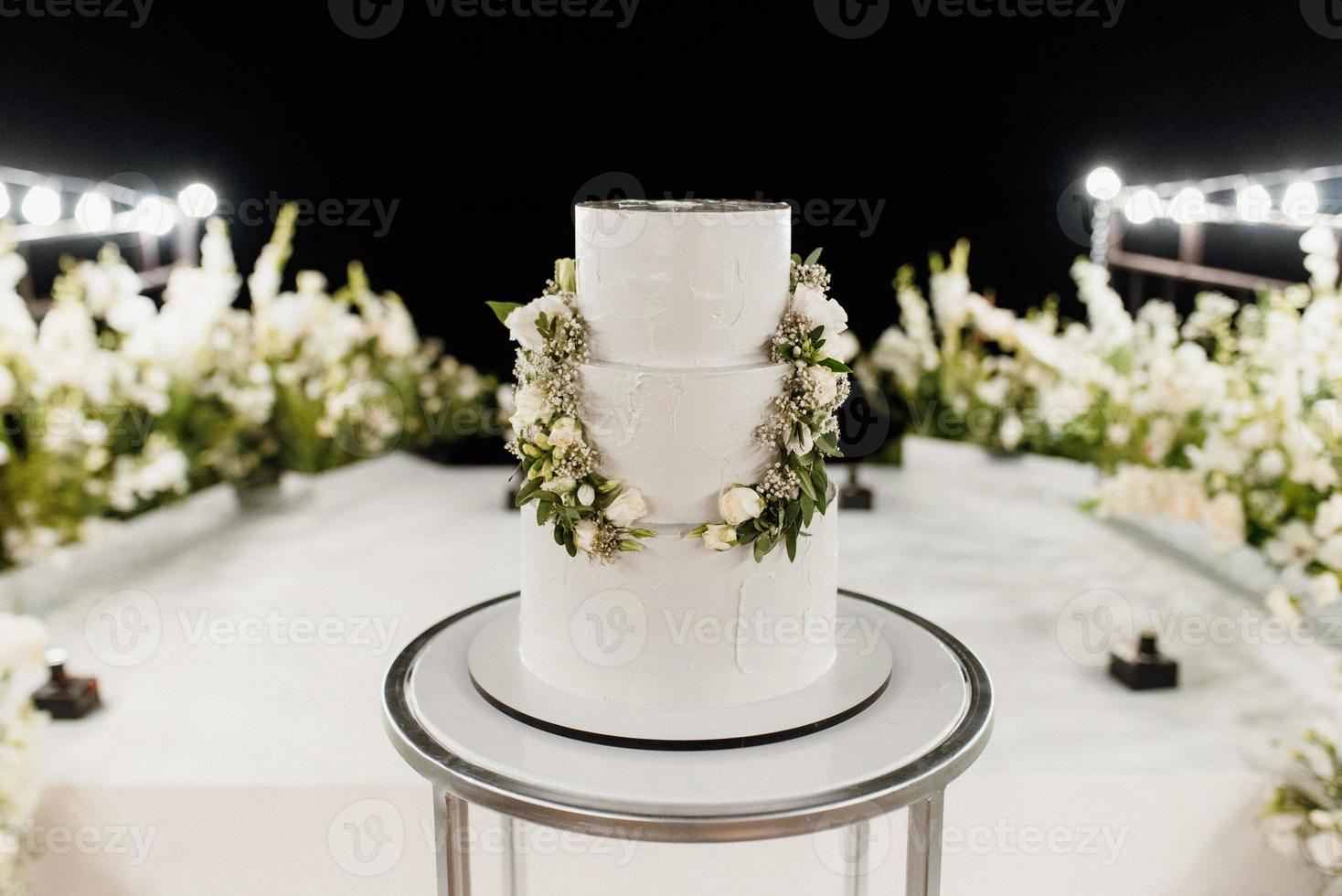 wedding white cake on a high stand near the white podium photo