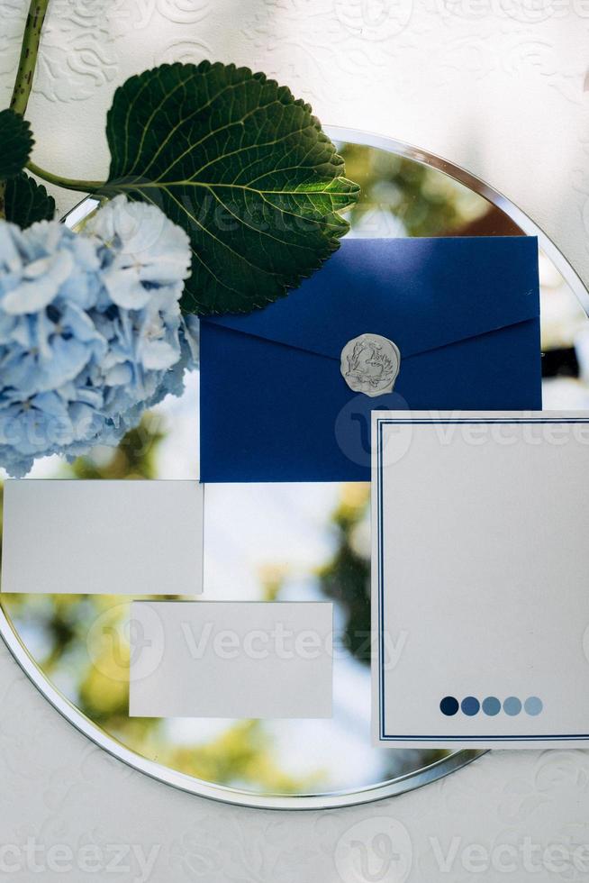 wedding invitation in a gray envelope on a table with green sprigs photo