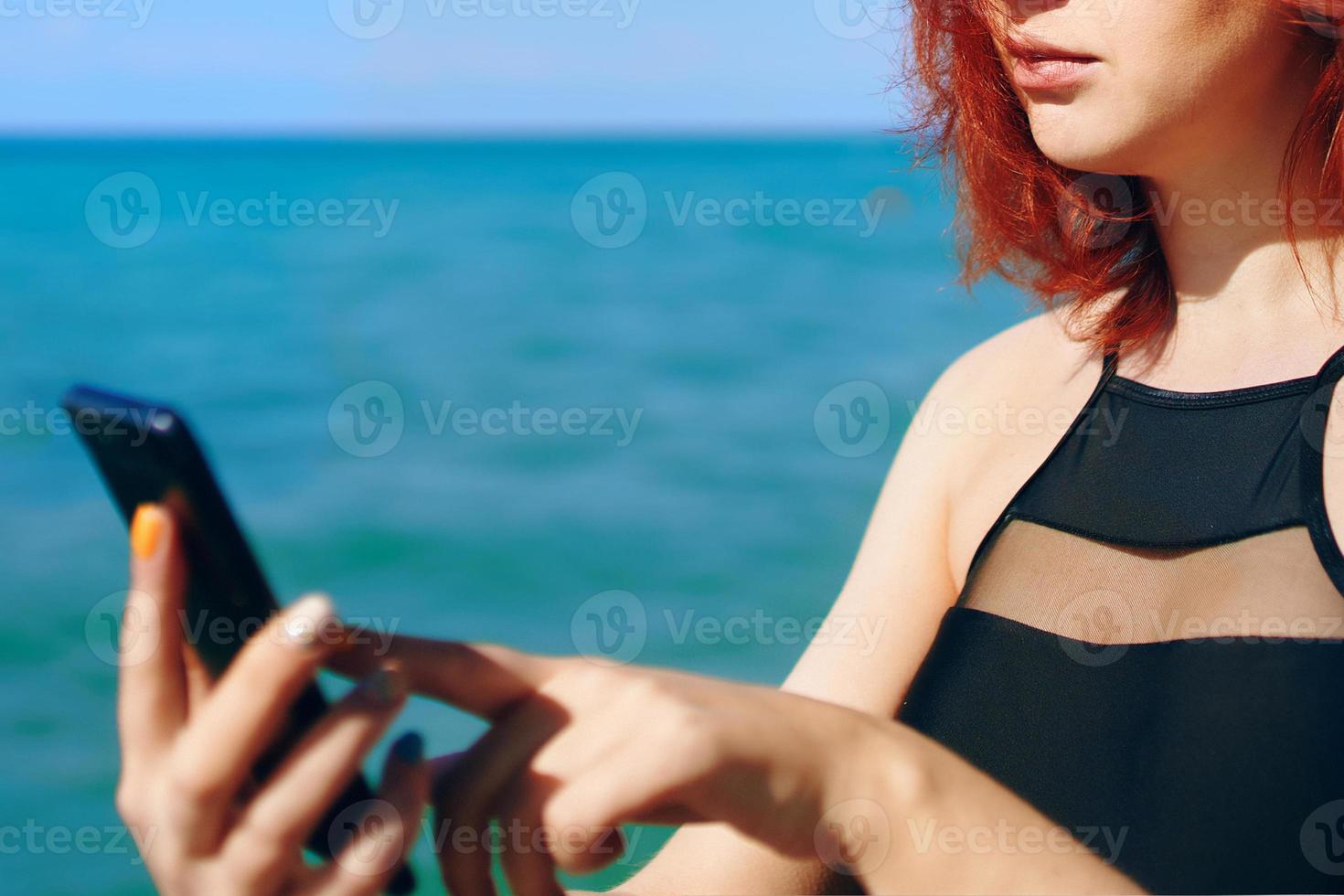 Red-haired woman writes message on her mobile phone photo