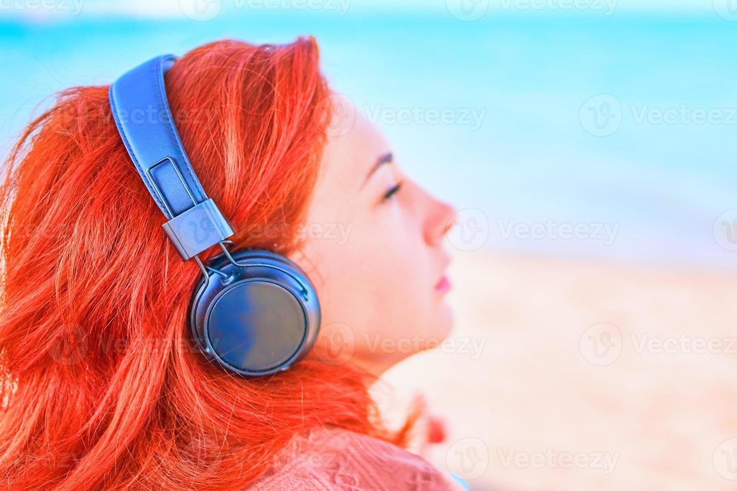 Beautiful woman listening to music on the beach photo