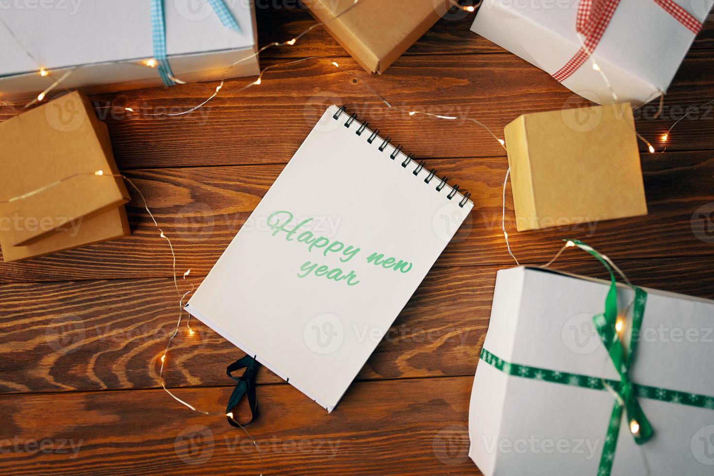 Wooden table with gift boxes and notepad. photo