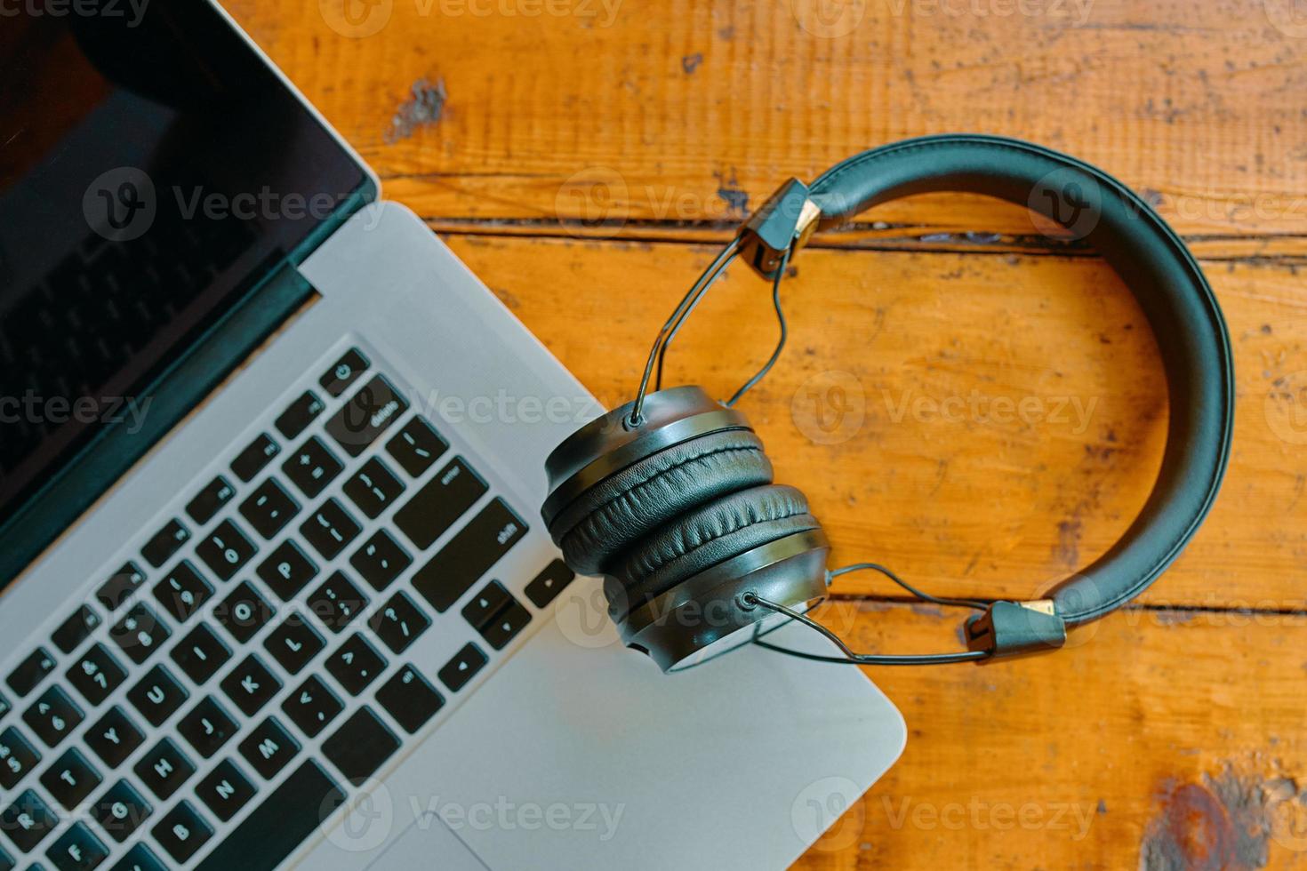 Flat lay of laptop and wireless headphones on wooden table. photo