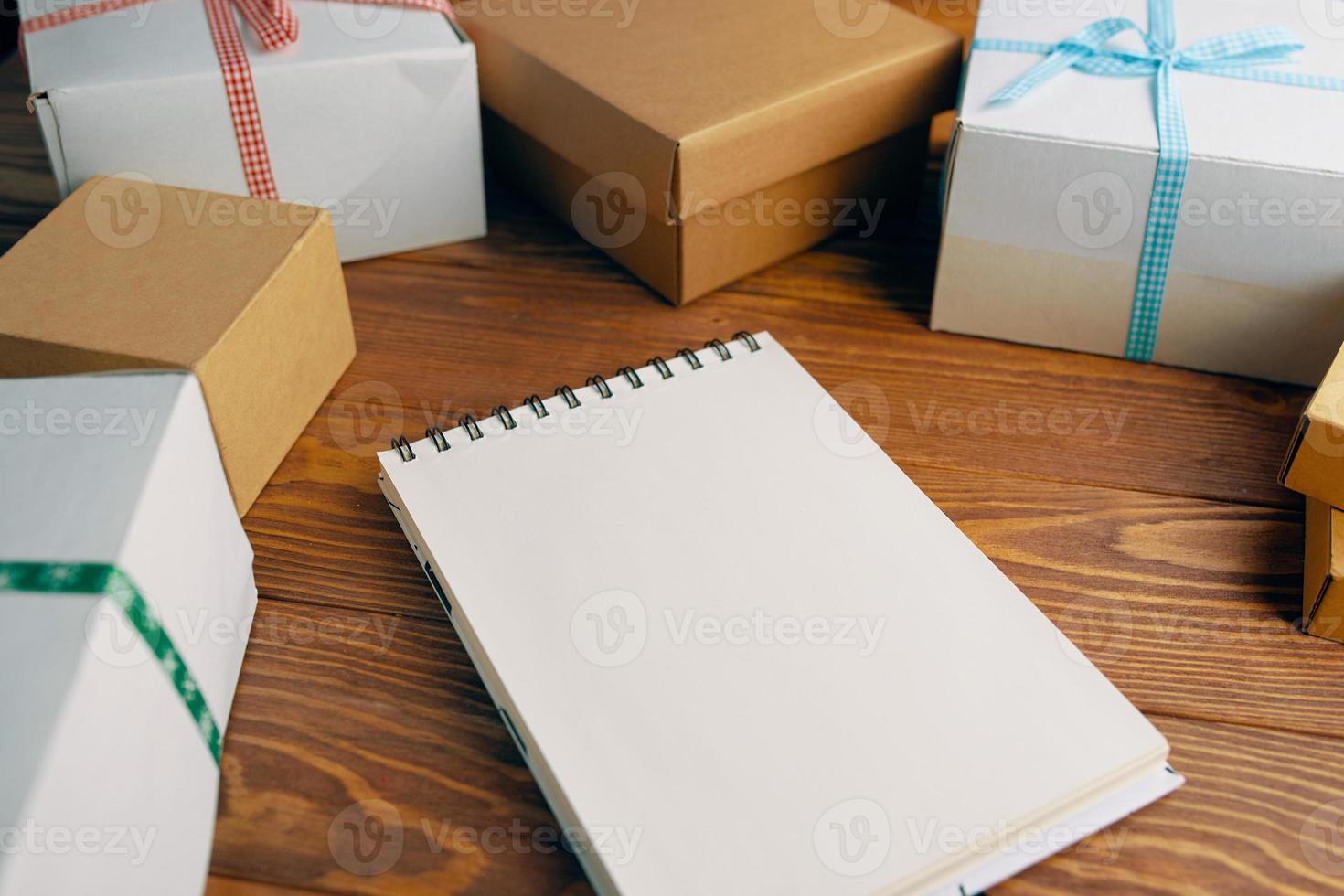 Wooden table with gift boxes and blank notepad. photo