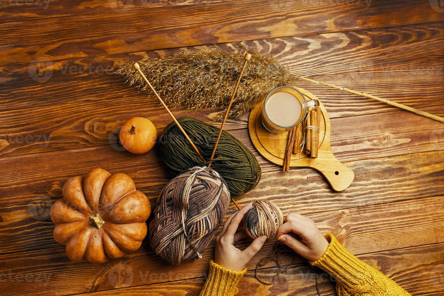 Manos de mujer con bola de hilo, calabaza, café sobre fondo de madera. foto