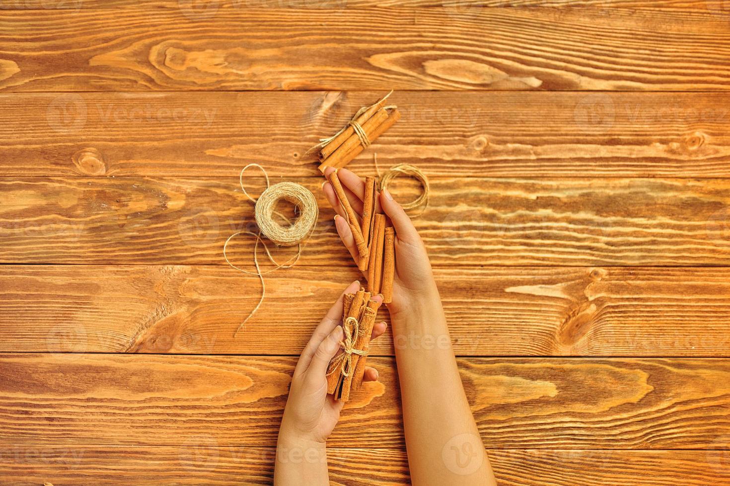 Cinnamon sticks in hands on a wooden background. photo