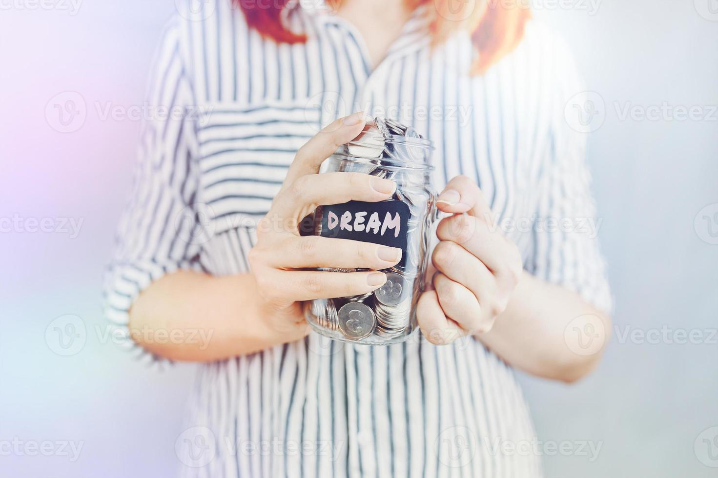 Woman holds glass jar of coins for her dream. photo