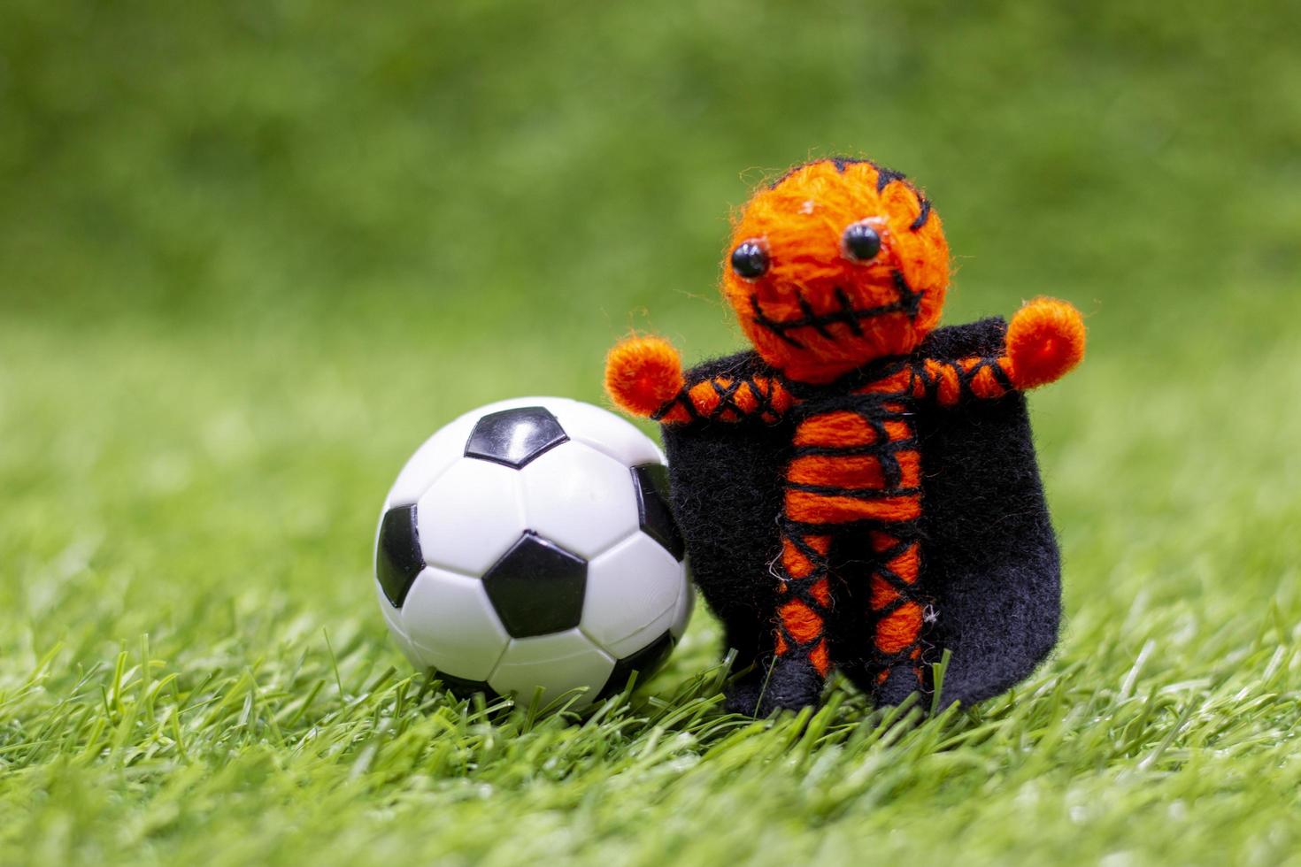 Soccer ball with ghost are on green grass on Halloween day photo