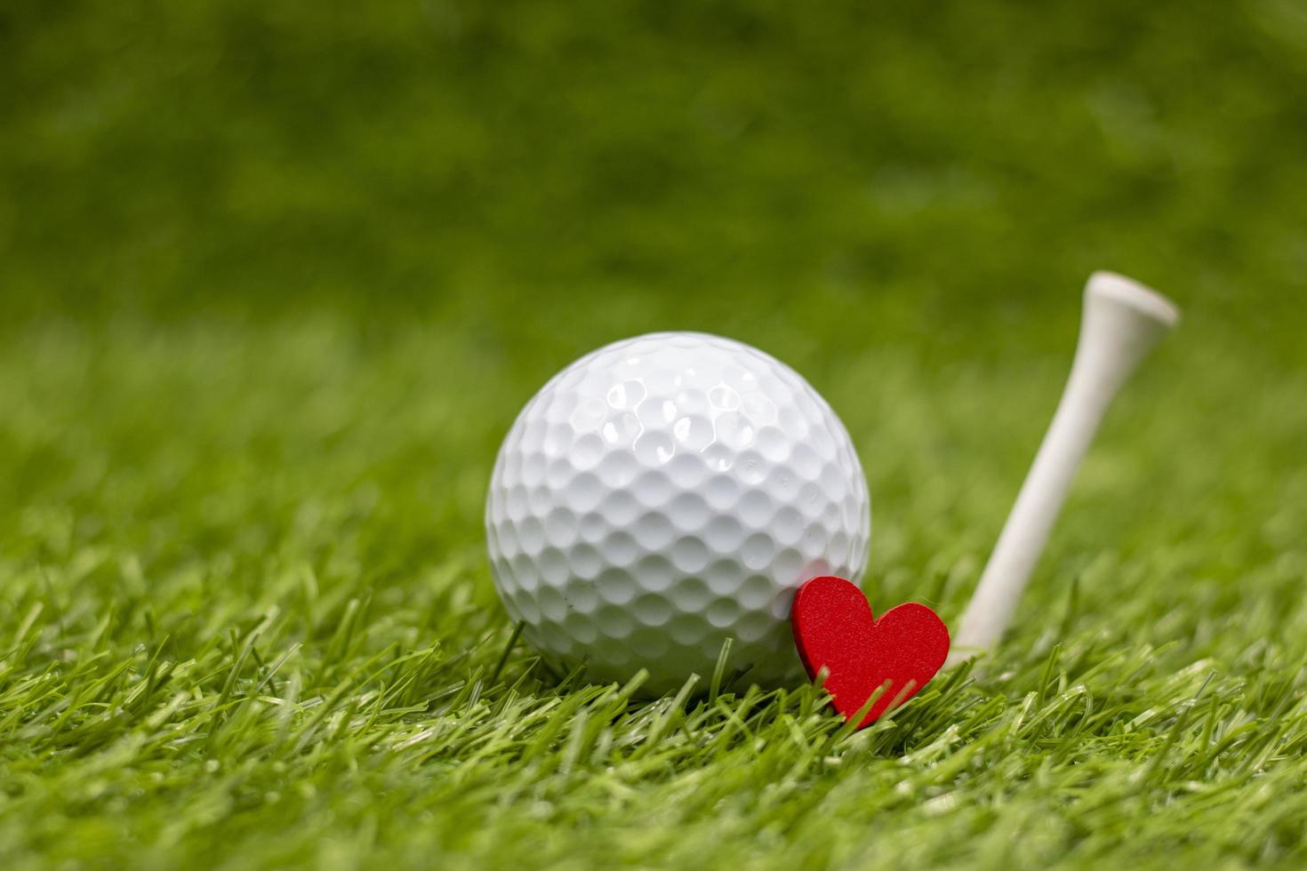 Golf ball with tee is on green grass with love photo