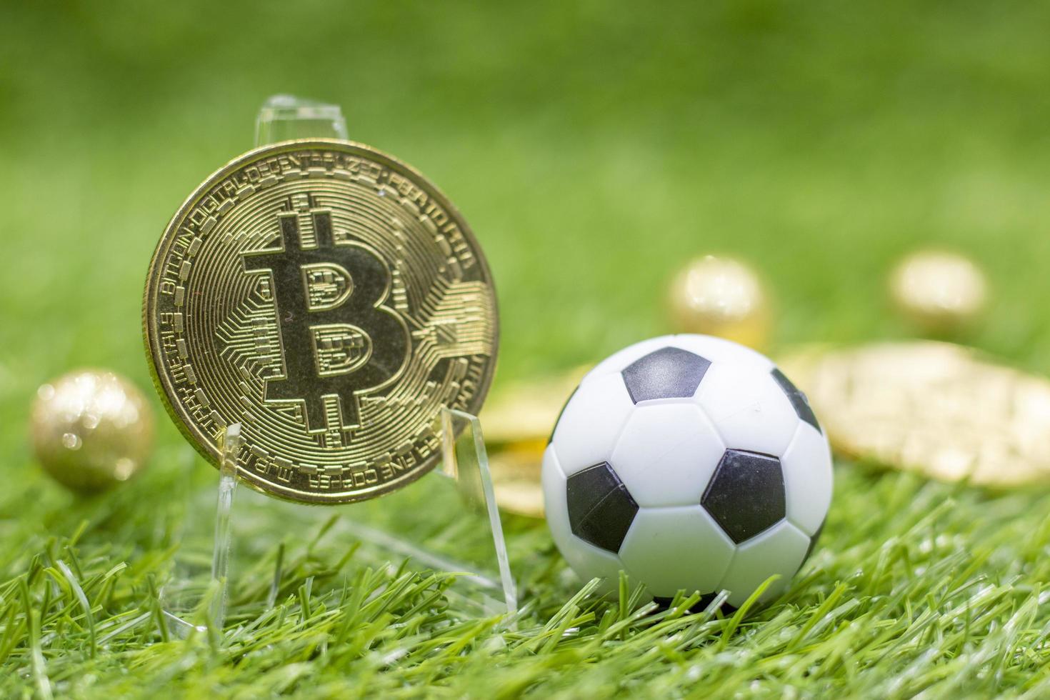 Bitcoin with soccer ball on green grass backrground photo